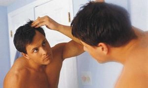 hombre mirando su cabello al espejo